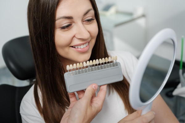 Eine Patientin bekommt verschiedene Farbtöne von Veneers gezeigt